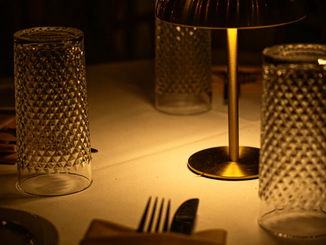 Gedeckter Tisch mit Tischleuchte und geschliffenen Gläsern