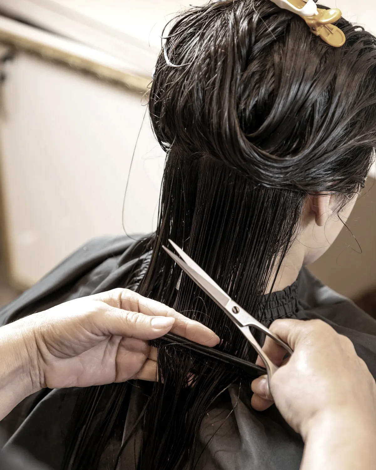 Hände schneiden nasses Haar mit einer Schere